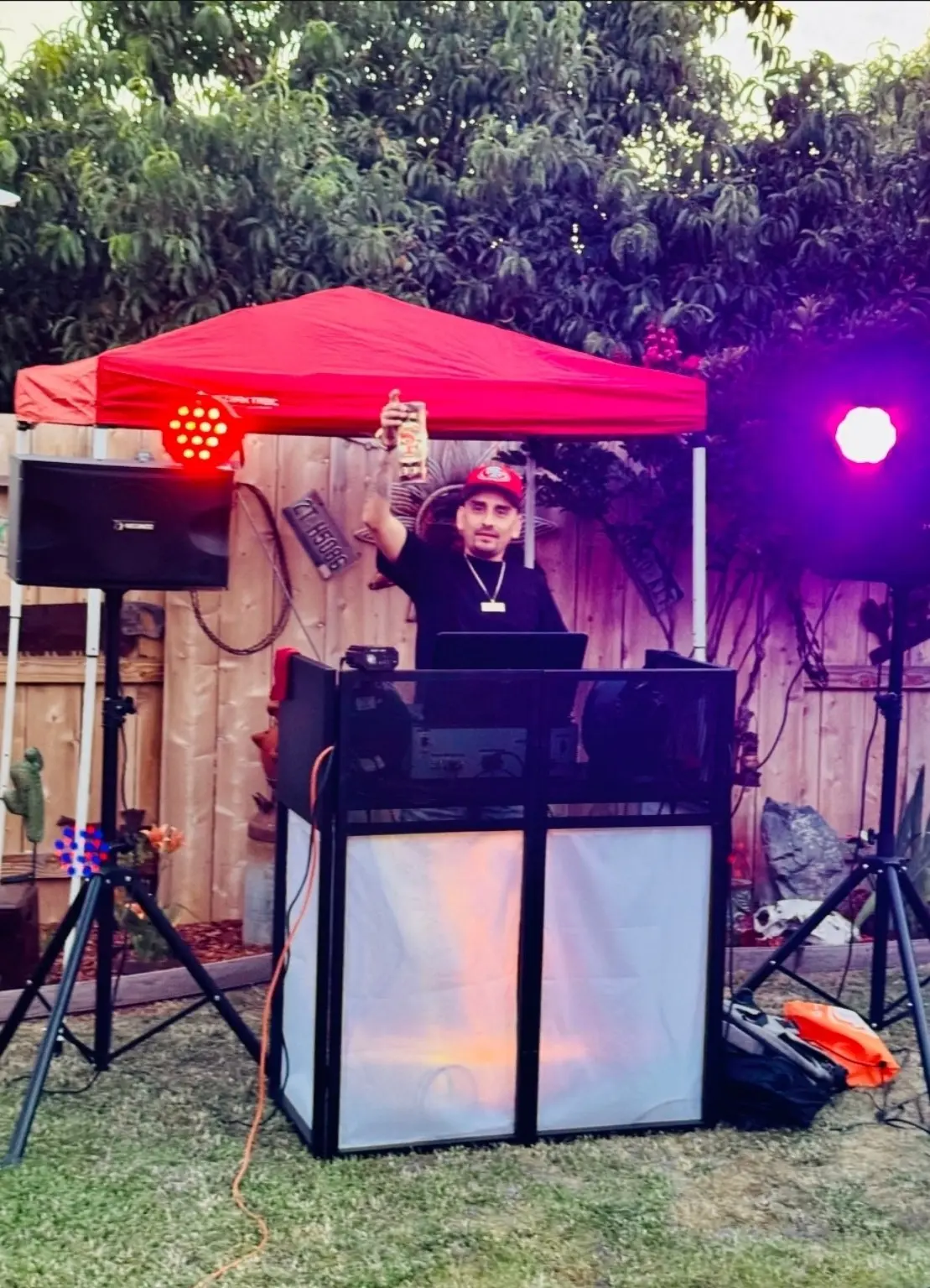 DJ JRV performing outdoors with professional speakers and colorful dance floor lighting